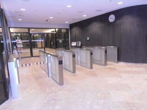 Zutrittskontrollierter Reflexzugang mit DRV-Bund-Zugangssystemen Drehkreuzen und Wanduhr im großzügigen Foyerbereich