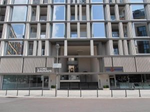 Erleben Sie feines Wohnen: Modernes Bauhaus-Wohnhaus mit Einzelhandelsflächen im Erdgeschoss und symmetrischen rechteckigen Fenstern
