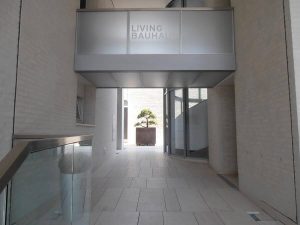 Erleben Sie minimalistische Architektur vom Feinsten: Ein modernes Wohngebäude mit „Living Bauhaus“-Beschilderung und modernsten Zugangskontrollsystemen