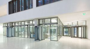 Lobby eines modernen Bürogebäudes mit transparenten Sicherheitskarusselltüren und deutschen Notausgangsschildern für effiziente Ein- und Ausgänge