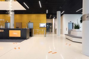 Erleben Sie den modernen Büro-Empfangsbereich im 50Hertz Netzquartier Berlin: Eine Fusion aus Stil und Funktionalität mit auffälligen gelben Akzenten und einzigartigem Fußabdruck-Design auf dem Boden!