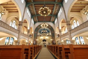 Erleben Sie die majestätische Pracht der Berliner Rykestr-Synagoge mit ihren hohen Decken, kunstvollen Kronleuchtern und altmodischen Holzbänken
