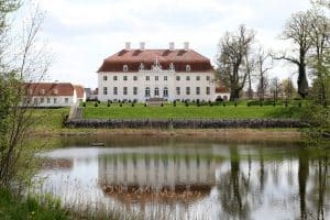 Entdecken Sie die Pracht eines historischen Herrenhauses mit Terrassengarten und Teichreflexionen: Eine Reise durch Eleganz und Geschichte
