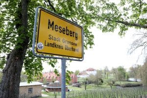 Dies ist ein Foto eines gelben Straßenschildes, das in Richtung der Stadt Meseberg weist, die innerhalb der Stadtgrenzen von Gransee im Landkreis Oberhavel liegt. Im Hintergrund des Bildes ist auch eine ruhige ländliche Landschaft zu sehen.